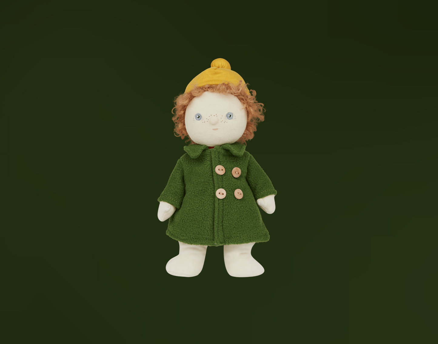 Toy doll with curly red hair, blue eyes and freckles wearing a green buttoned coat and yellow hat on a dark background
