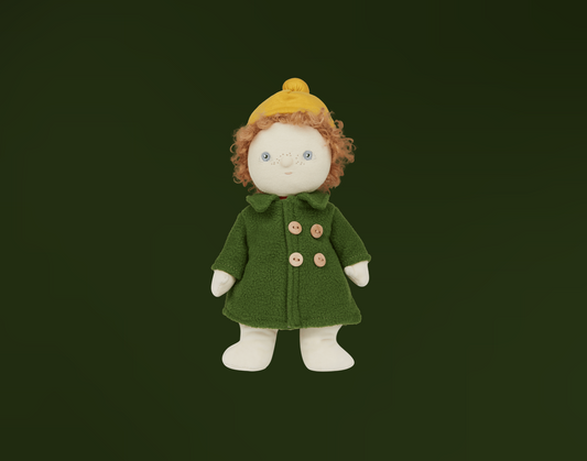 Toy doll with curly red hair, blue eyes and freckles wearing a green buttoned coat and yellow hat on a dark background