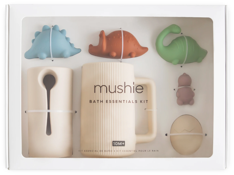 Mushie dinosaur bath essentials kit with various colorful dino  bath toys on a white background