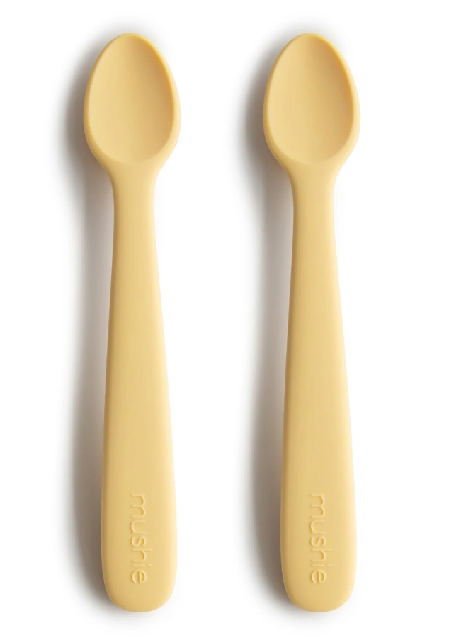 Two yellow silicone toddler spoons on a white background