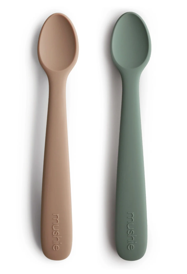 Two spoons, one brown and one green, on a white background with 'mushie' branding.