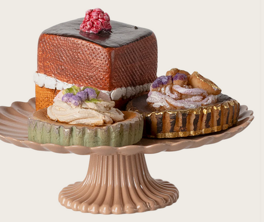 Decorative dollhouse cake stand with three miniature cakes on a white background