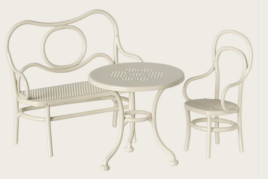 White metal outdoor furniture set with bench, table, and chair on a light gray background