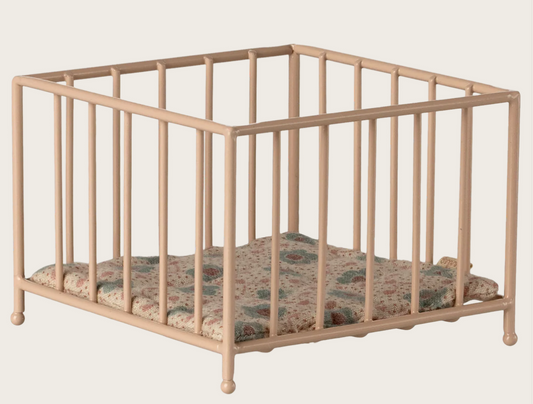 Beige metal dollhouse crib with floral mattress on a beige background
