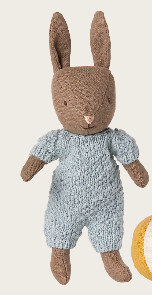 Knitted toy rabbit in a blue outfit on a beige background
