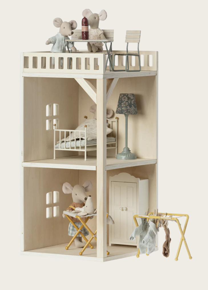 Wooden dollhouse with miniature furniture and toys on a white background