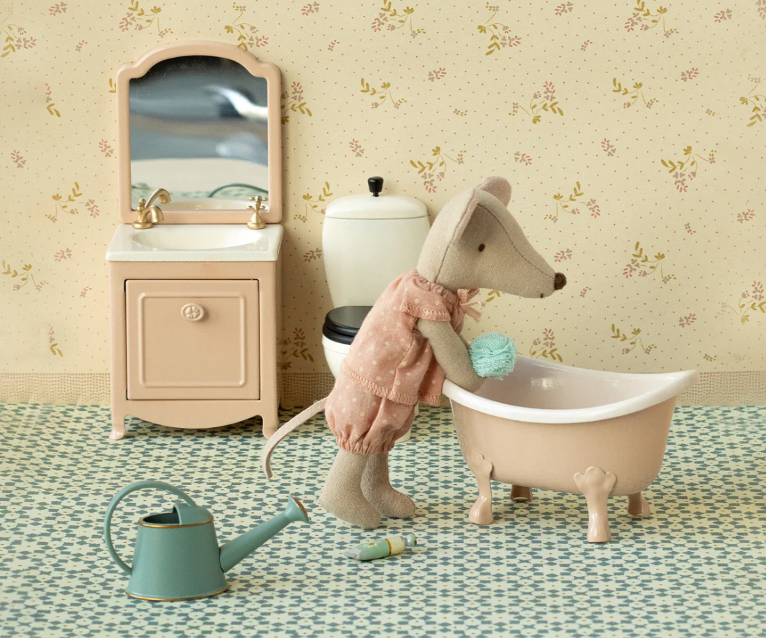 Toy mouse in a bathtub with a sink and mirror in the background