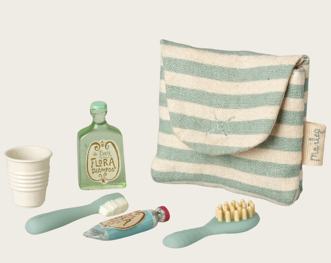 Mouse doll toiletry set with blue-striped bag, shampoo bottle, cup, toothbrush, toothpaste, and hairbrush on white background