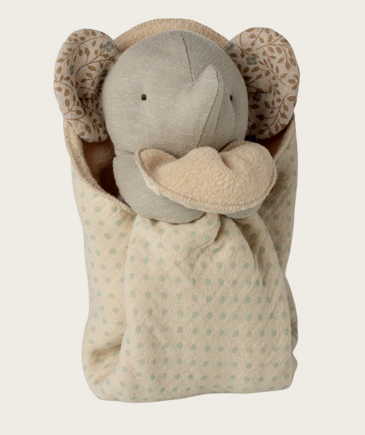 Stuffed elephant toy with floral ears wrapped in a patterned blanket on a light background