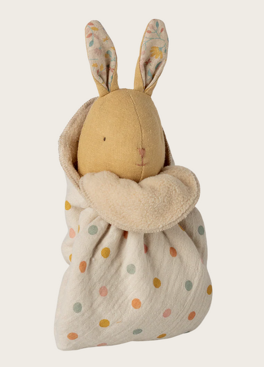 Toy rabbit wrapped in a polka dot blanket on a white background