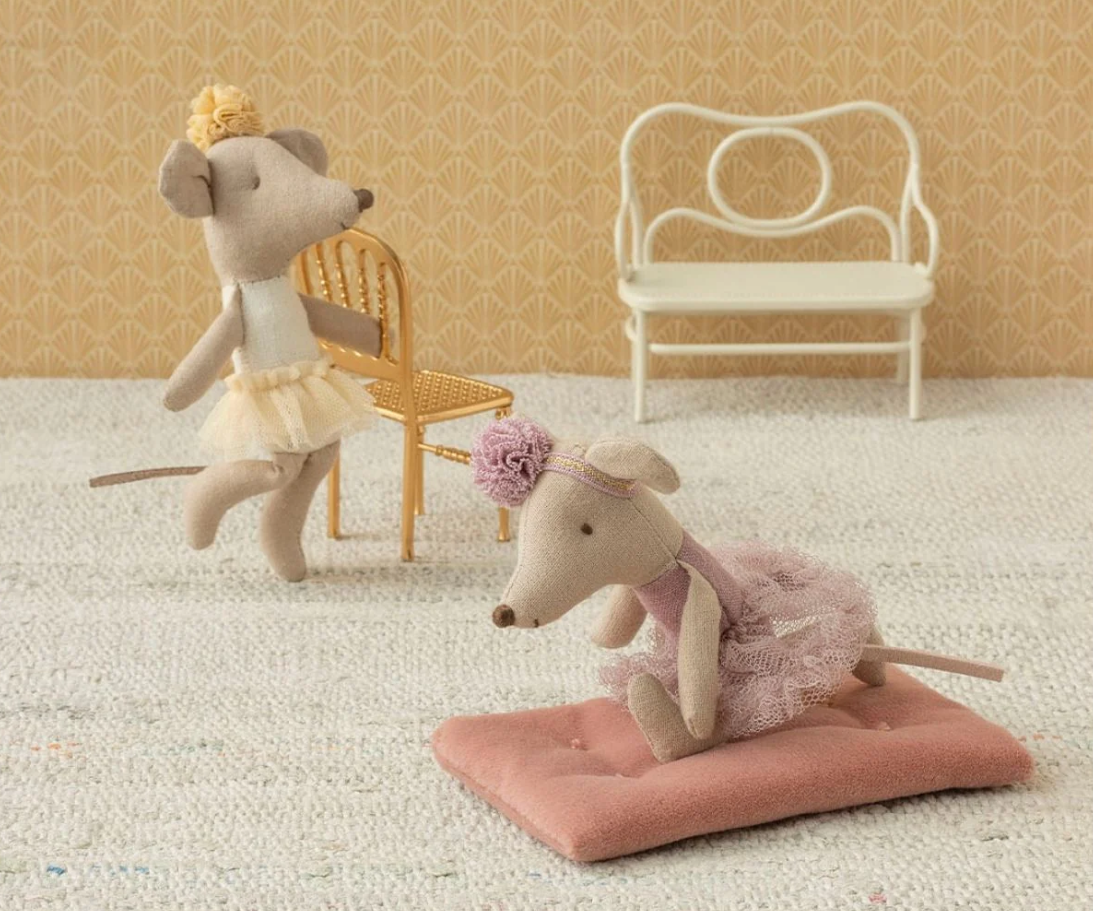 Two plush mouse toys in a decorative setting with a chair and pink cushion.