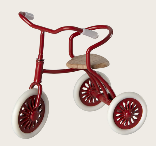 Small red toy dollhouse-sized tricycle on a white background