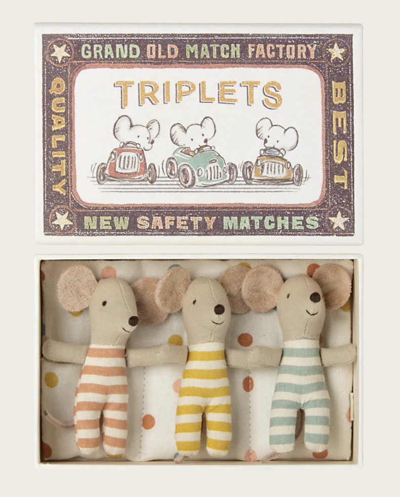 Three small mouse dolls in matchbox bed on white background