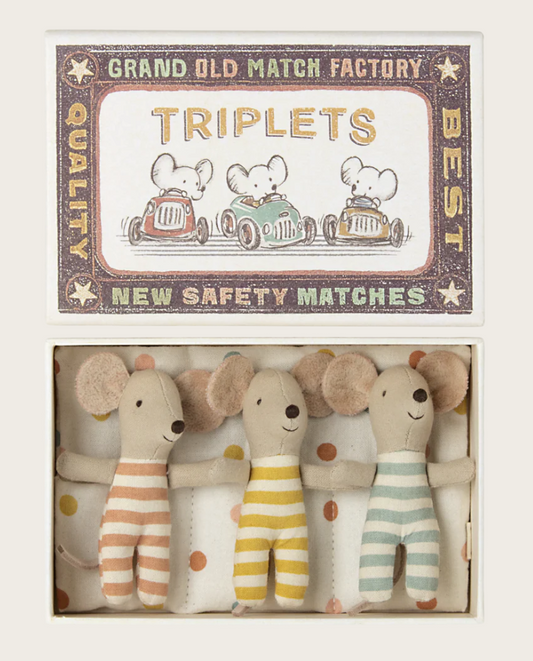 Three small mouse dolls in matchbox bed on white background