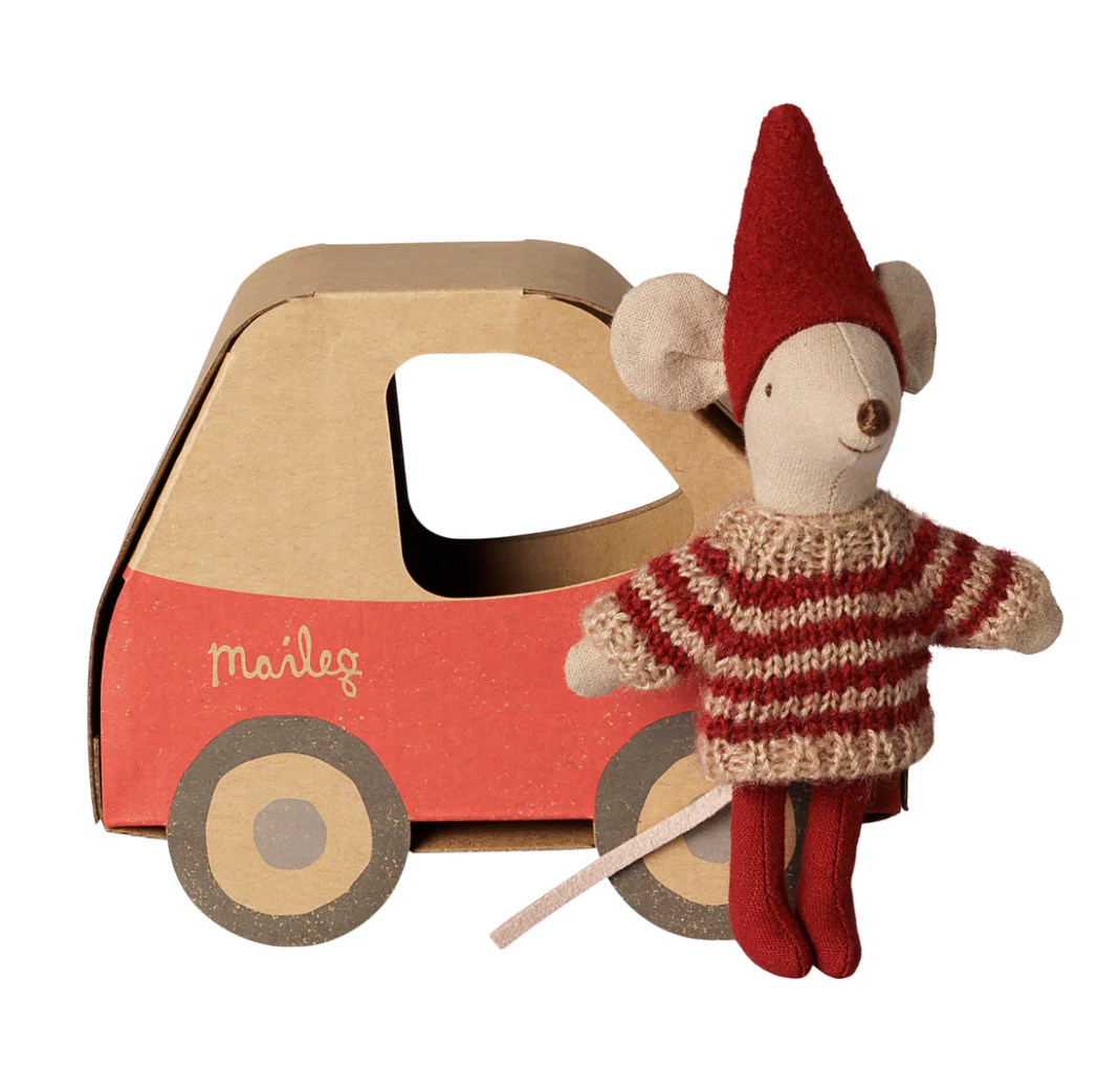 Maileg, little sister mouse with red elf hat and striped red and beige sweater on, standing next to cardboard toy car box