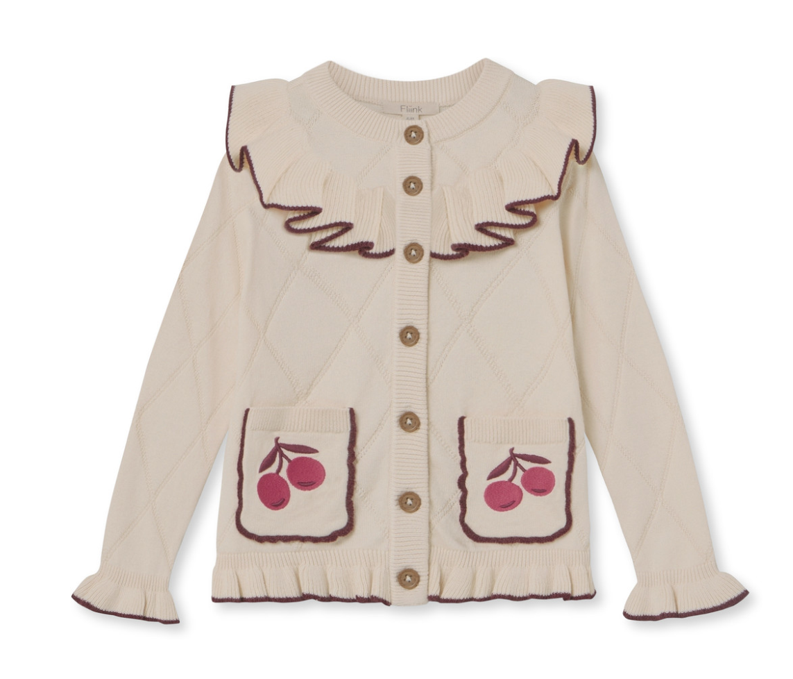 Ivory children's cardigan sweater with buttons down the front, a ruffle collar, sleeves and front pockets, edged in brown, with appliqued cherries on the pockets