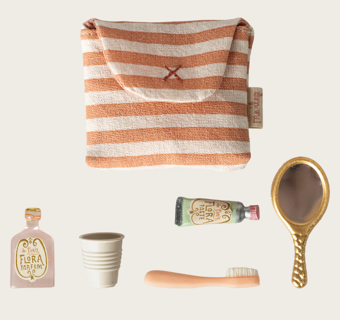 Tiny mouse doll toiletry set including a striped pouch, small bottle, cup, toothbrush, and mirror on a light background