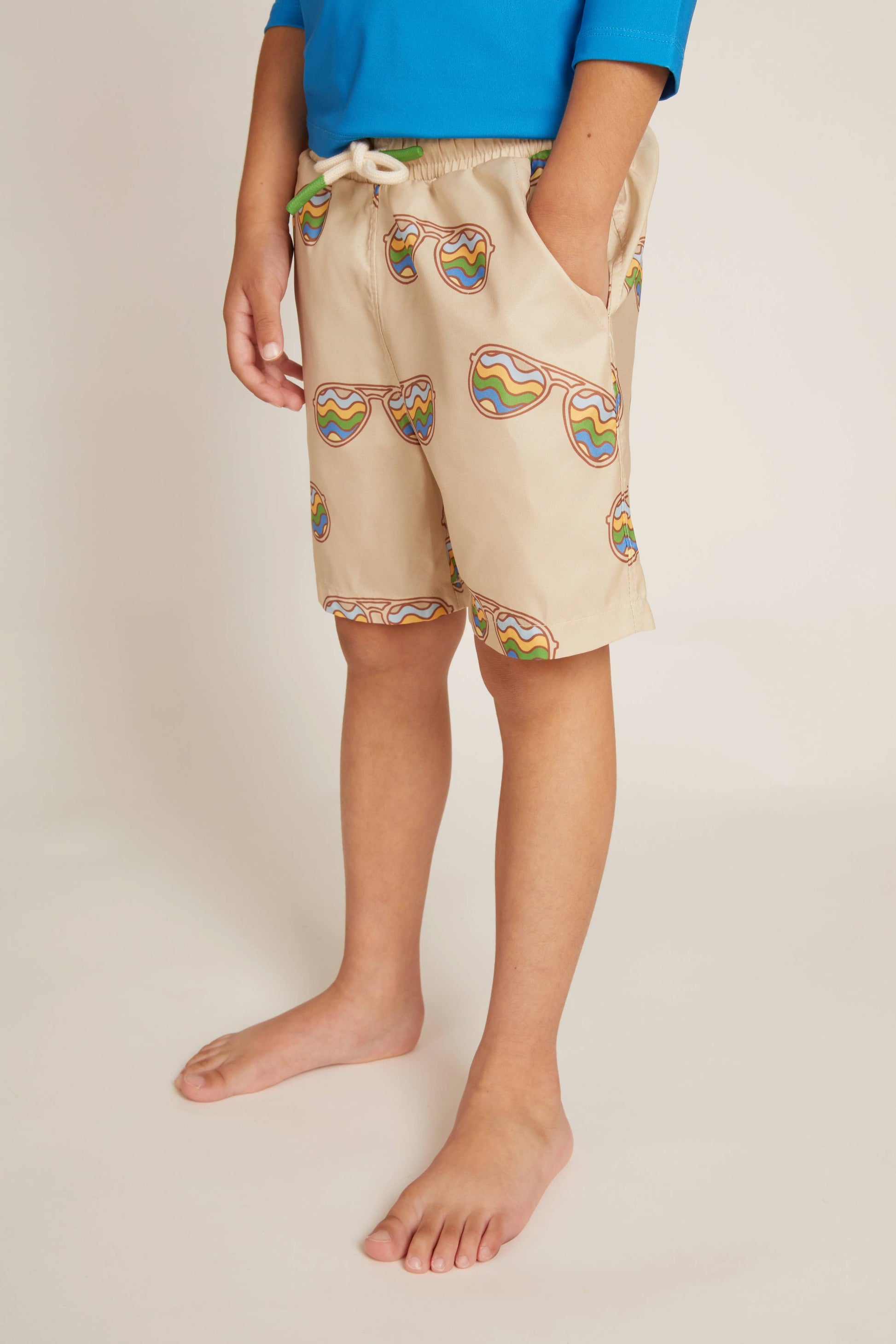 Beige shorts with colorful patterns worn by a person on a plain background