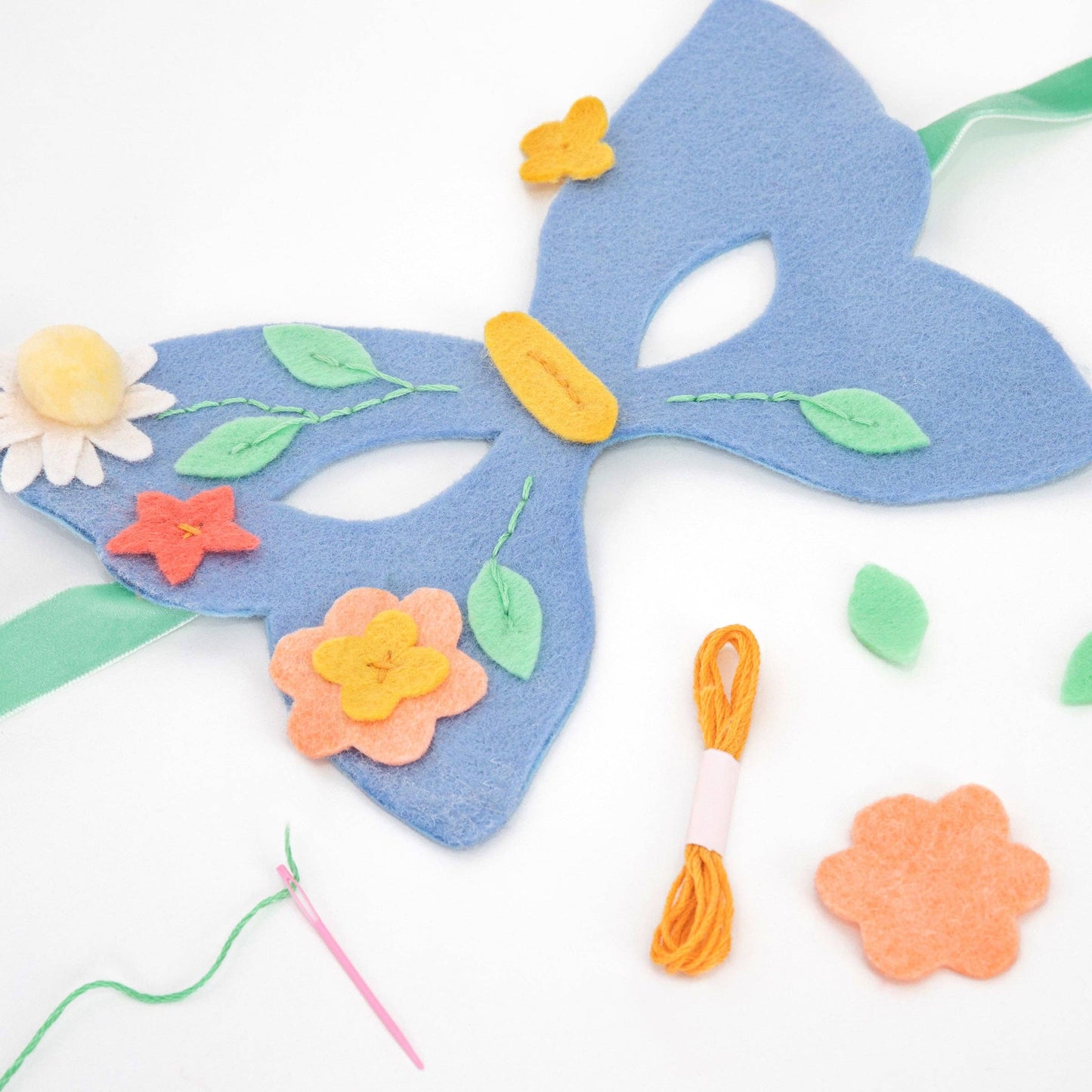 Blue felt mask with floral decorations on a white background