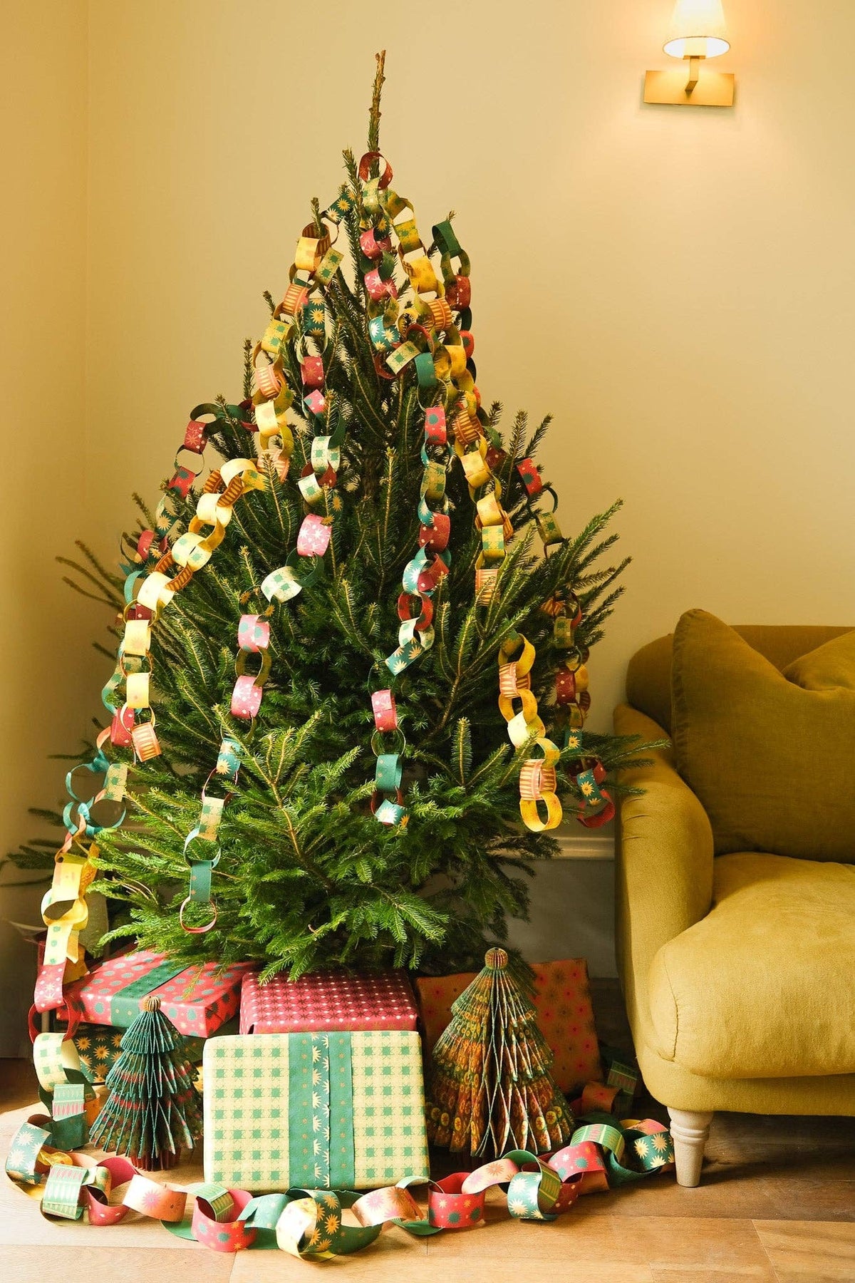 Christmas tree draped with colorful paper chains above wrapped presents and honeycomb paper trees.