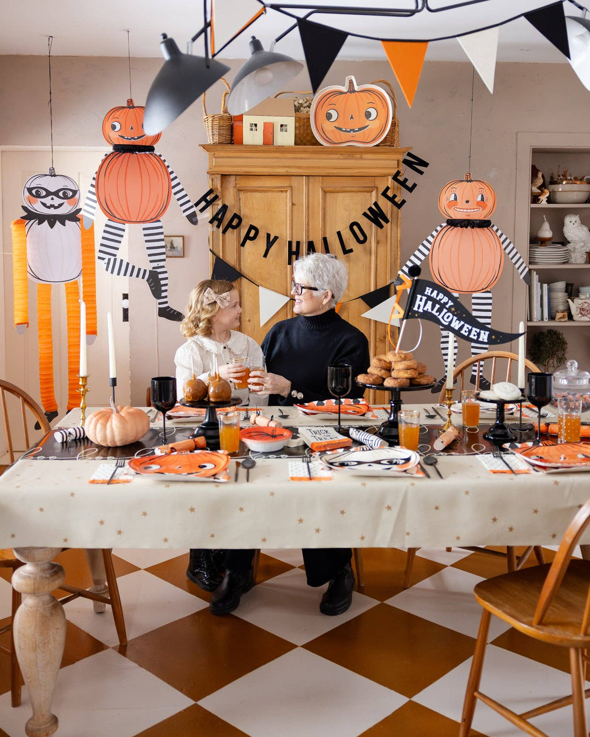 A woman and a child seated in a dining room that is decorated with Halloween decor.