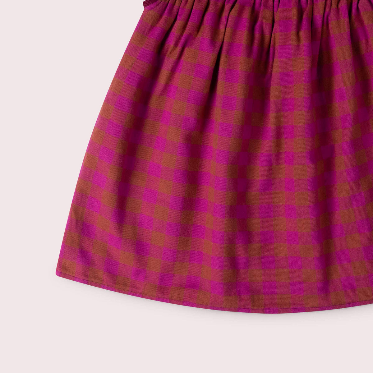 Detail of the pink and rust checked skirt and hem on a reversible swing dress.