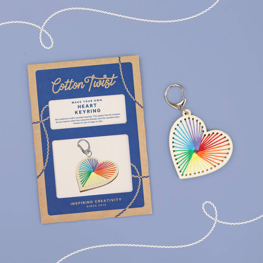 Heart-shaped keychain craft for children, with colorful design next to a packaging card on a blue background