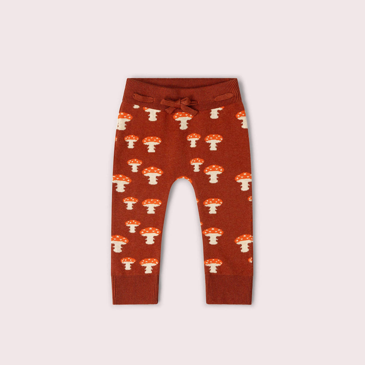 Rust knitted joggers with cream and red mushrooms, a tie waist and ribbed ankle cuffs.