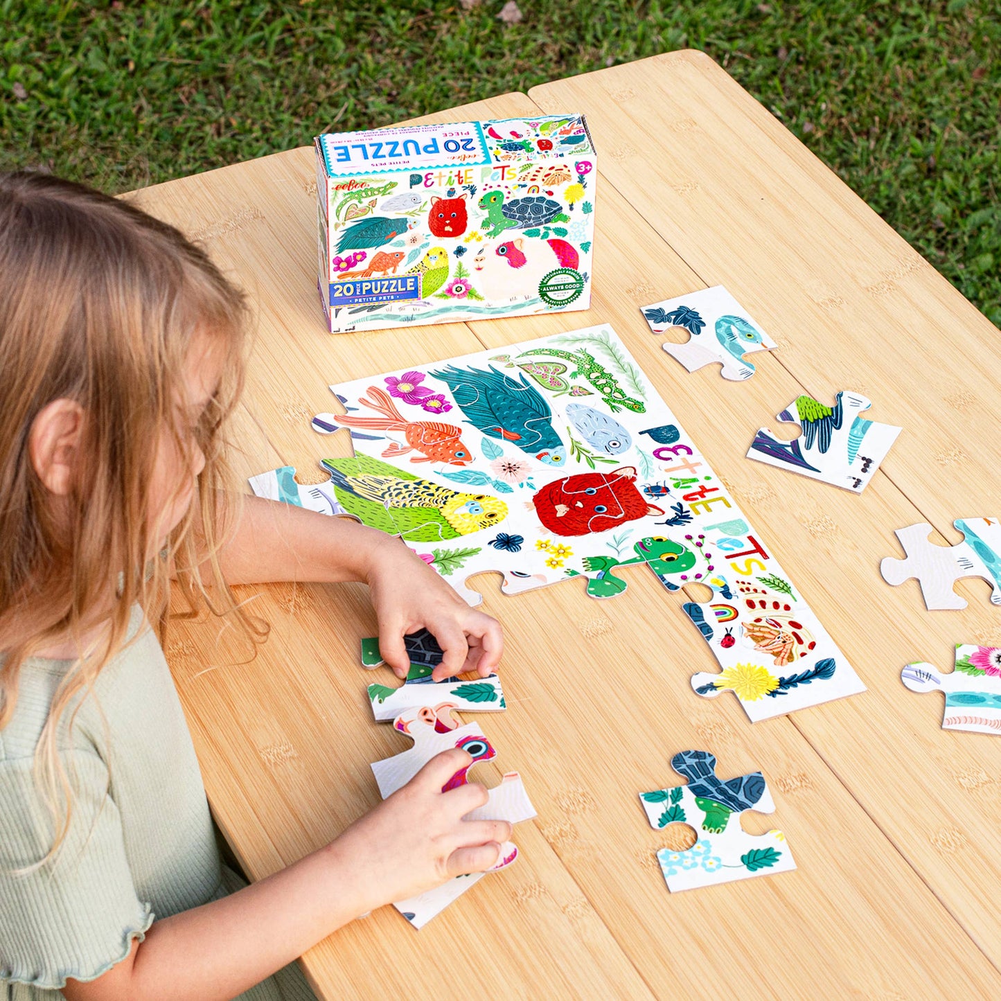 Child playing with a puzzle on a wooden table outdoors