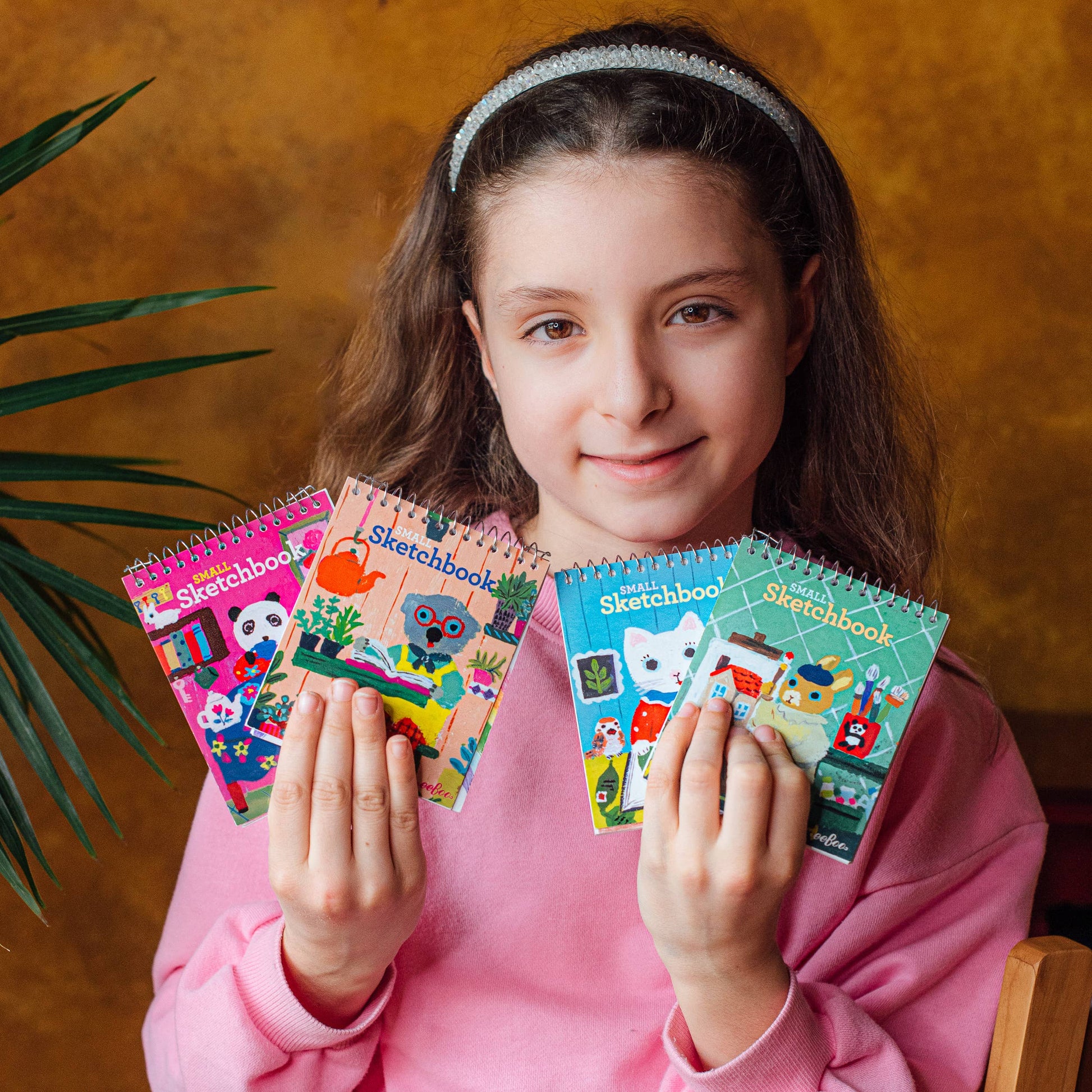 Girl holding colorful sketchbooks with a warm background