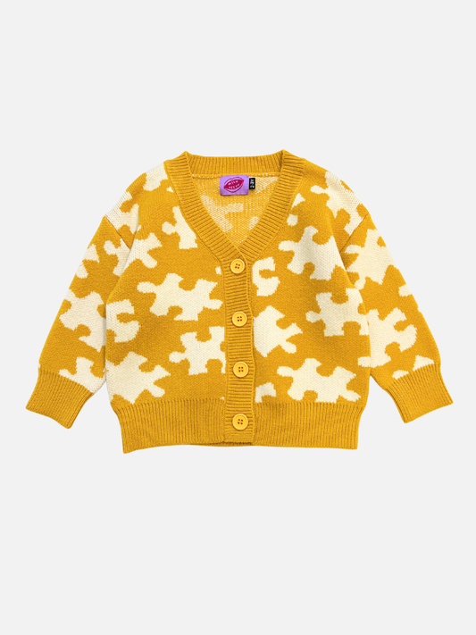 Yellow cardigan with white puzzle piece pattern on a light gray background