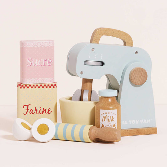 Set of toy kitchen items including a mixer, rolling pin, and containers with labels on a light background