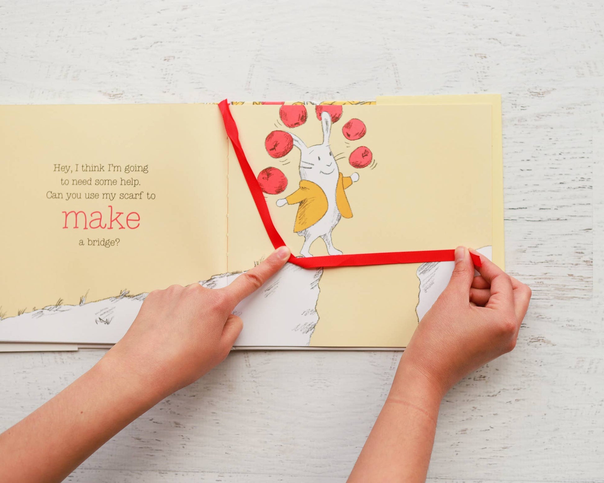 Children's book with a cartoon rabbit and red string, being used to tie a knot.