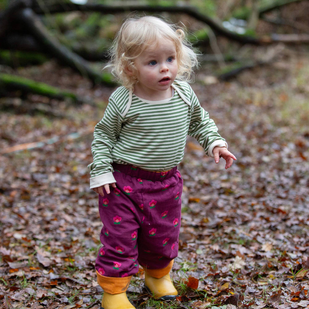 Child wearing Pink Flowers reversible pull-on trousers outdoors.