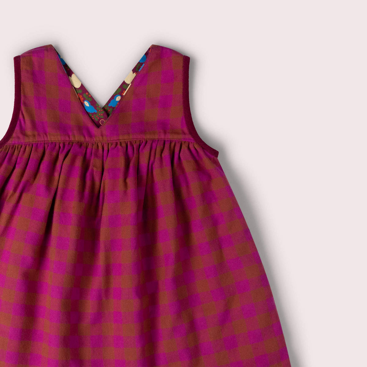 Close-up of the V-neckline and gathered waist on the checked side of a reversible dress.