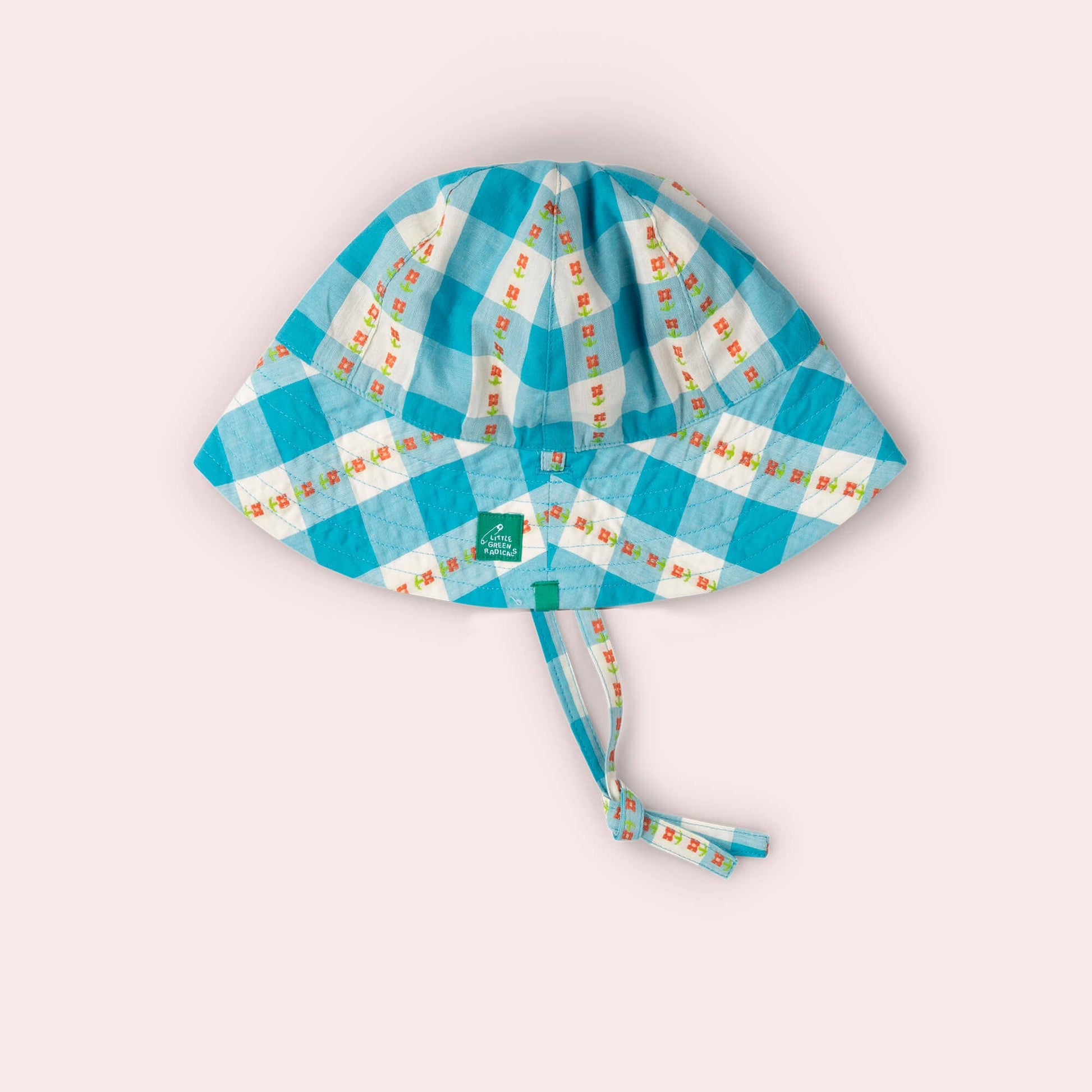 Children's checkered hat with a strap on a light pink background