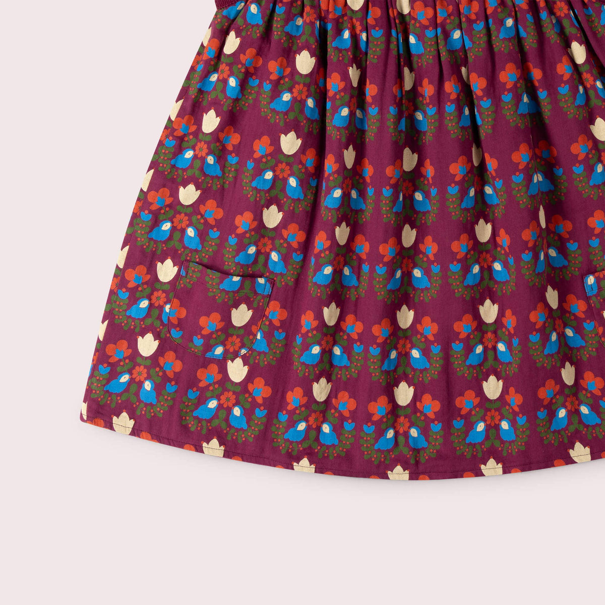 Detail of the patch pocket, bird-and-flower print and hem on a burgundy swing dress.