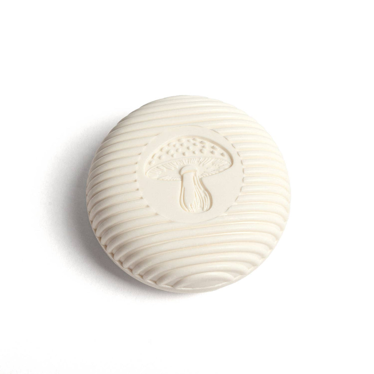 Round white Swedish Pine gnome soap with a raised mushroom design on a white background