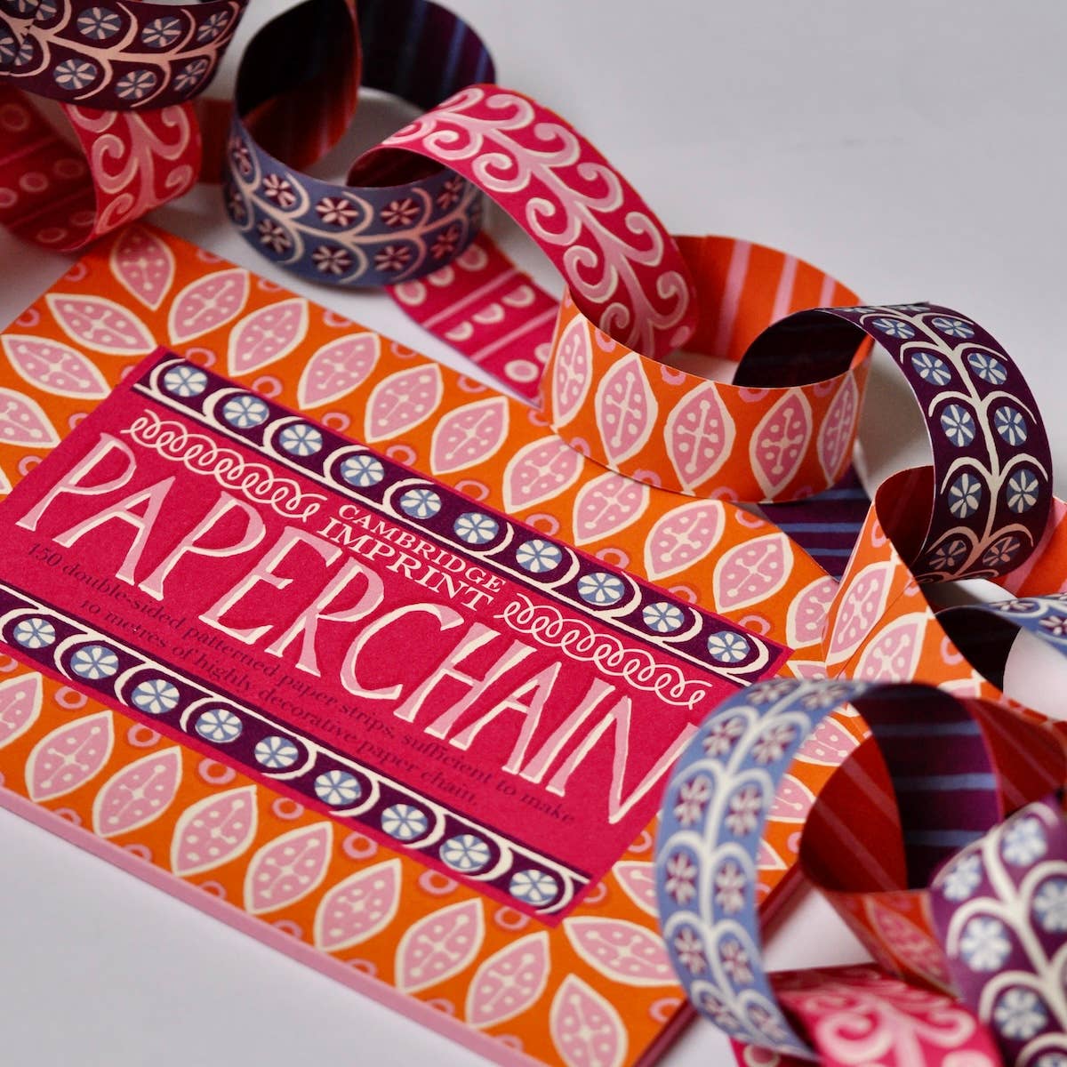 Paperchain 4 packaging surrounded by pink, orange, blue and purple patterned paper links.