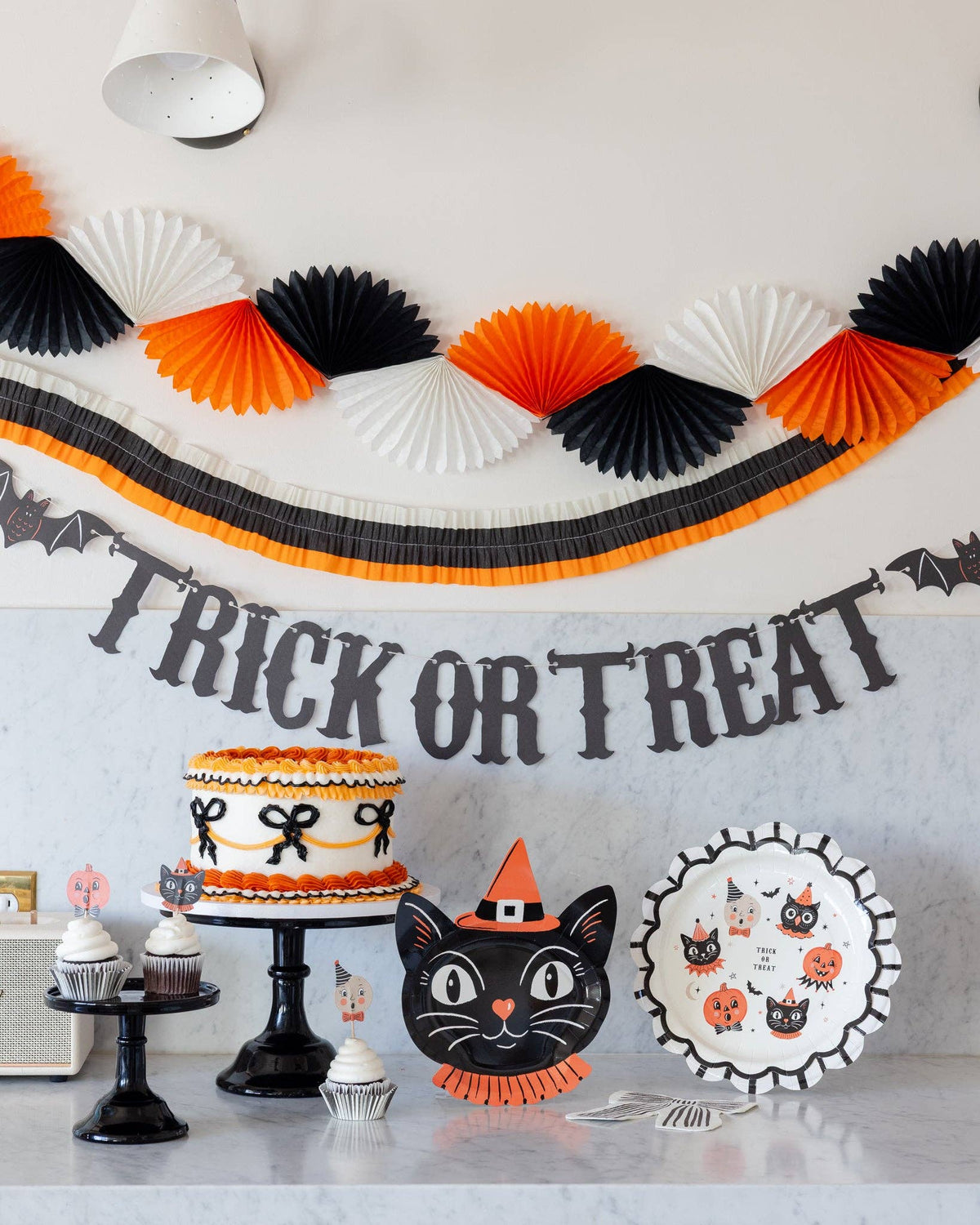 Halloween-themed party setup with decorations, cake, and treats on a table.