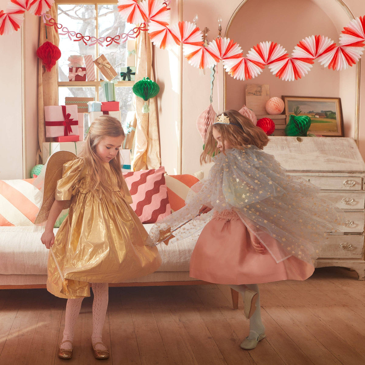 Two children in fairy costumes playing in a decorated room with Christmas decorations.