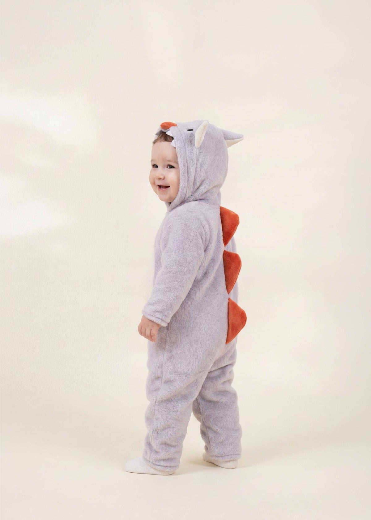 Child wearing a gray monster costume with red accents on a white background