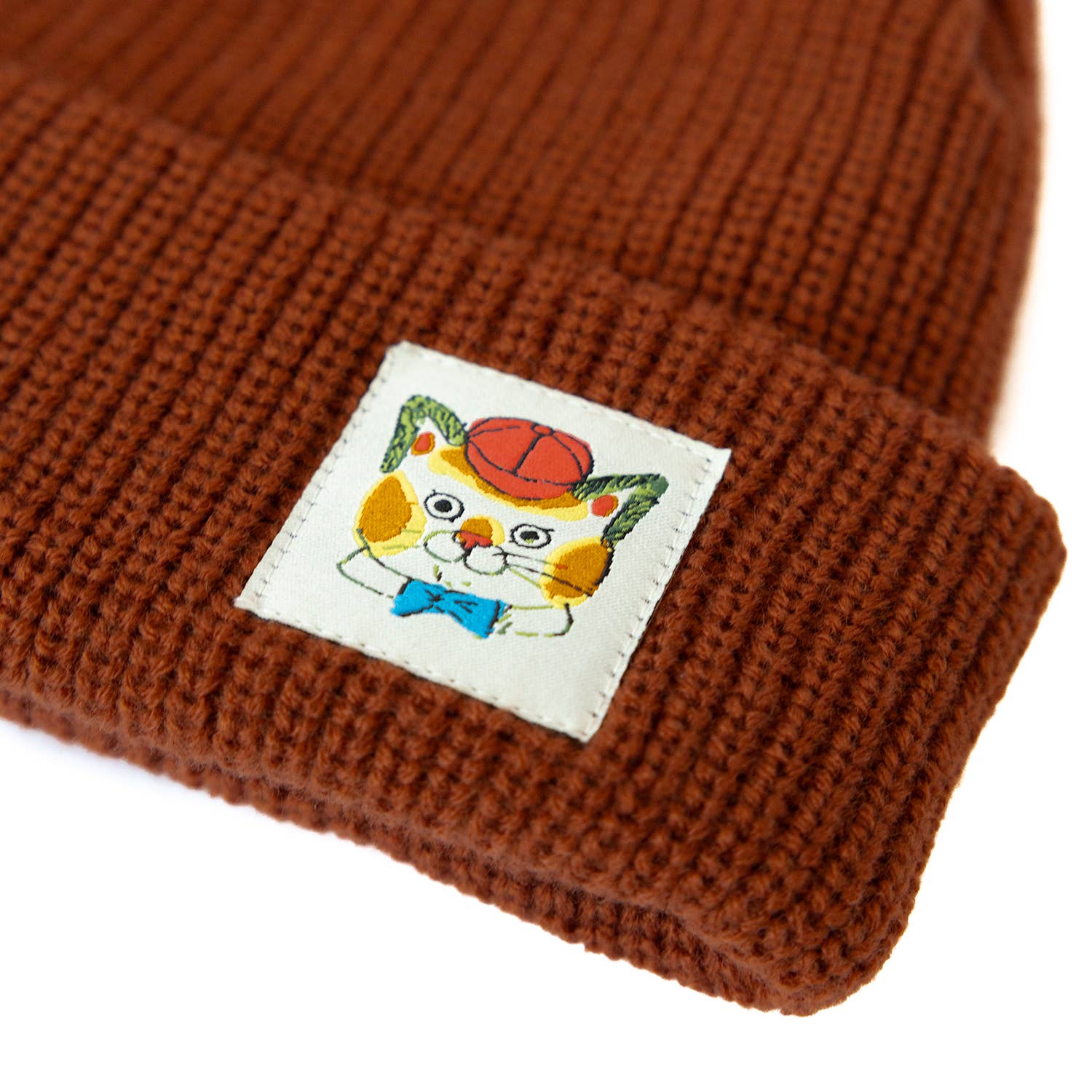 Brown knit beanie with a colorful cat patch on a white background