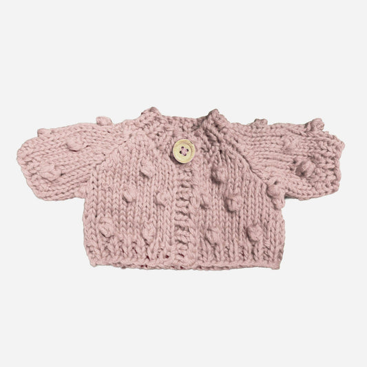 Pink knitted doll cardigan with a button on a white background