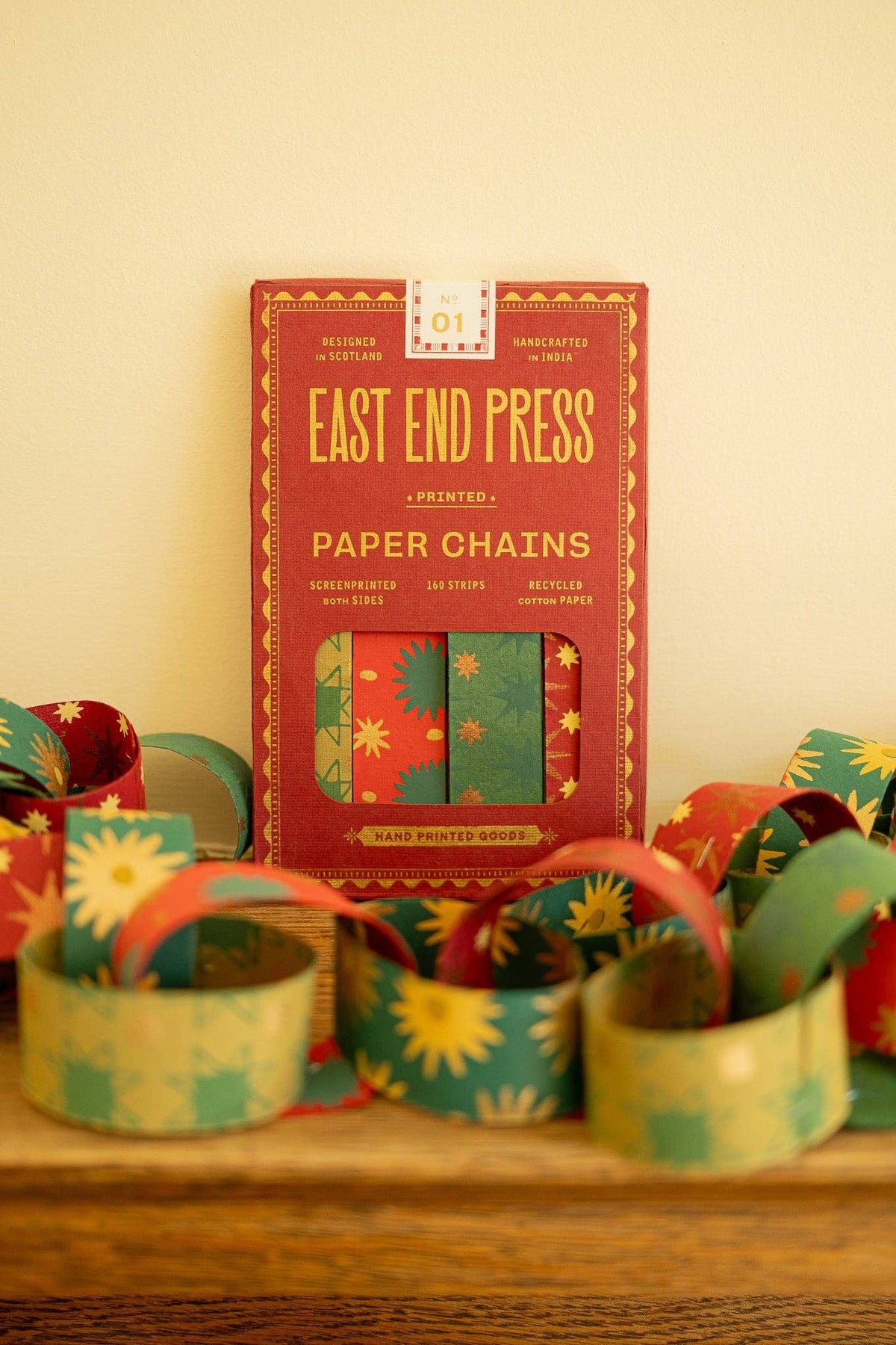 East End Press Festive Paper Chain Kit box surrounded by assembled red, green and gold paper links.