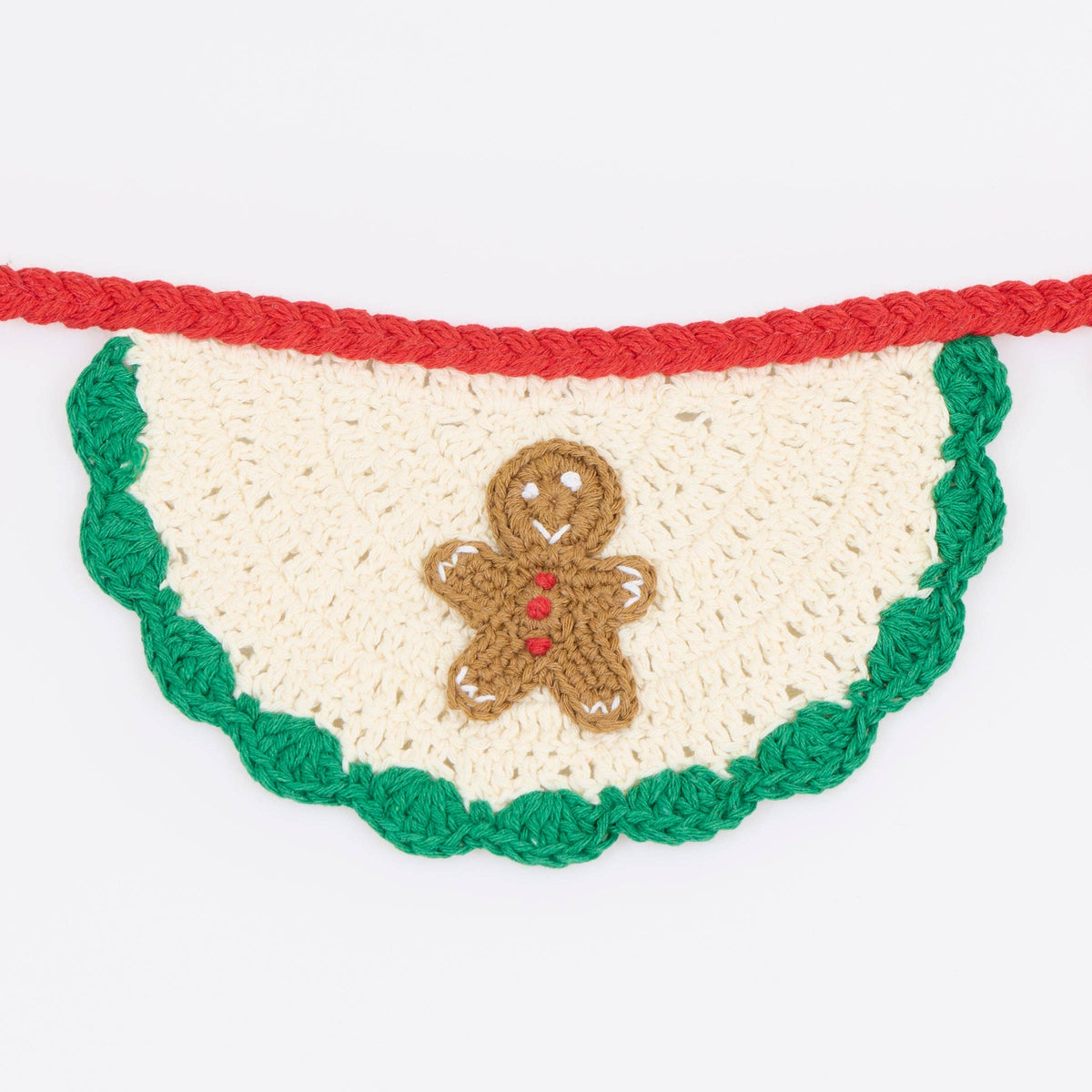 A crocheted Christmas garland banner with a scalloped green edge, a red top border, and a brown gingerbread man figure in the center, shown against a plain white background.