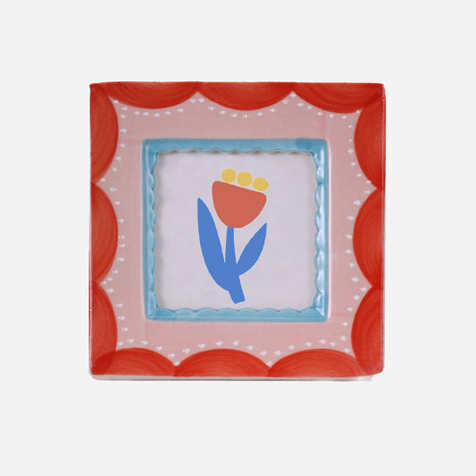 Decorative square frame with a floral design and scalloped red border on a white background