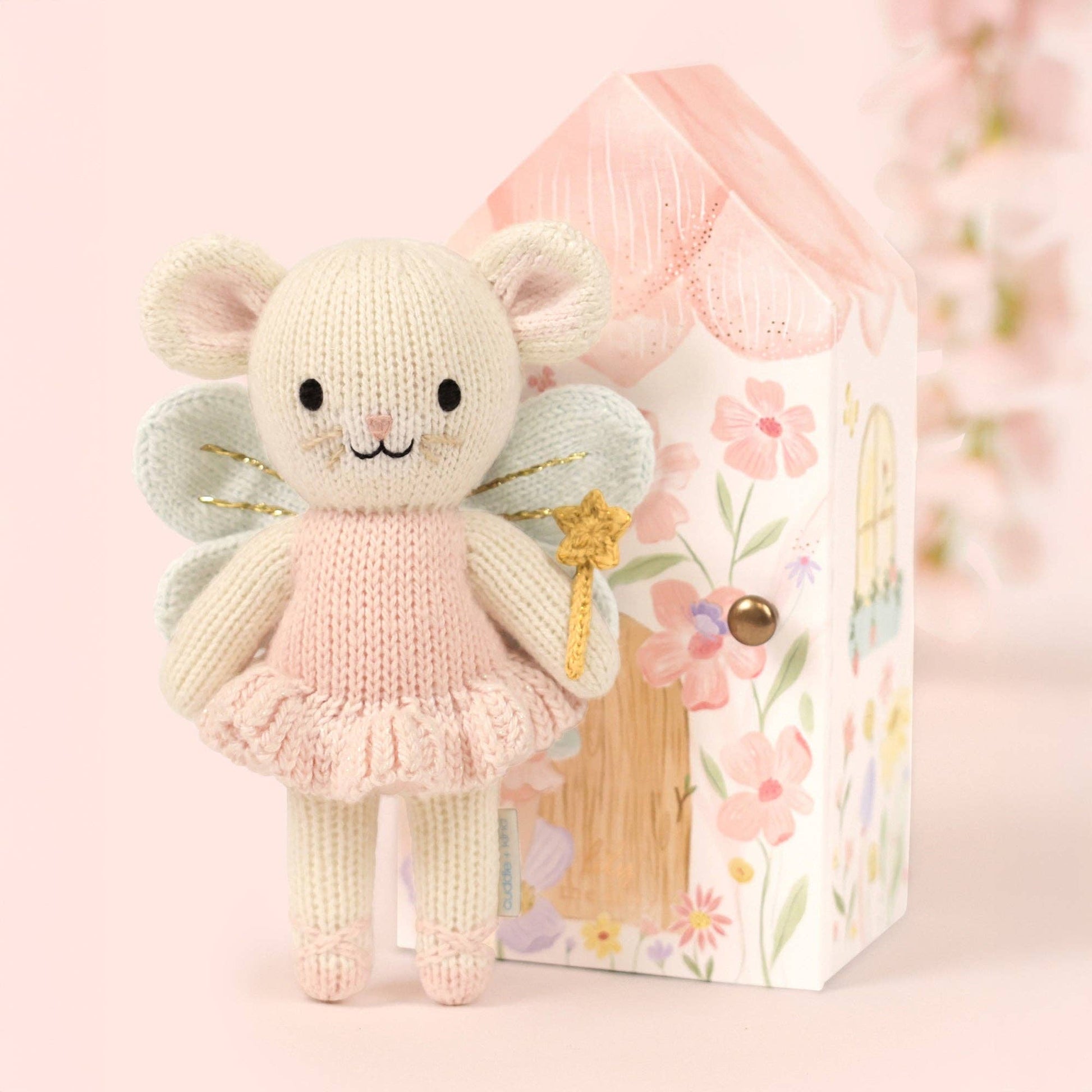 Knitted fairy toy with a floral box on a pink background