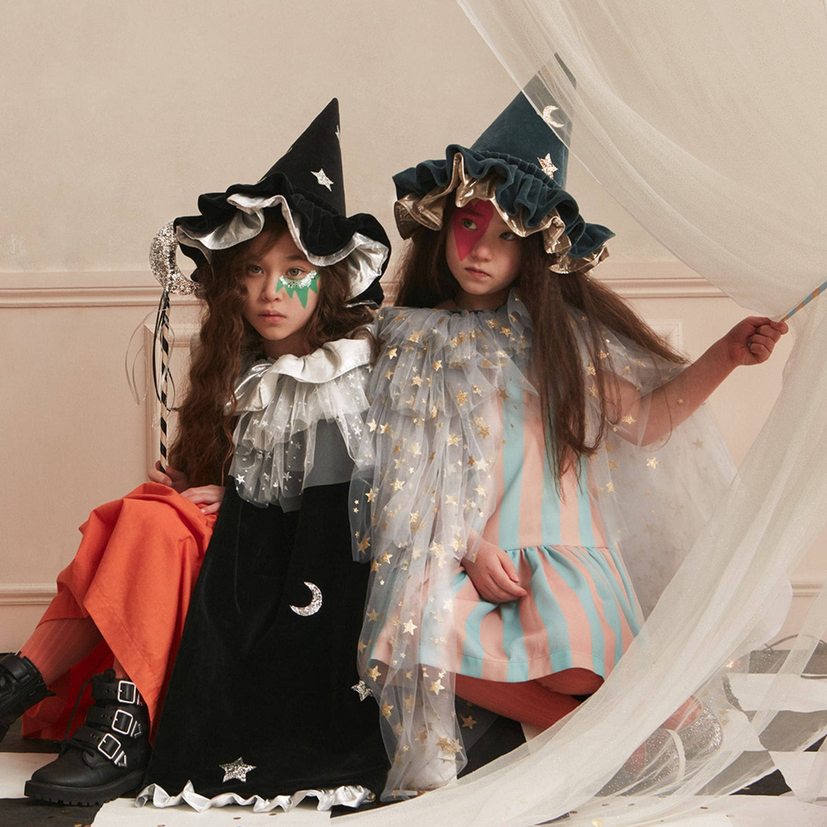 Two children in Halloween costumes with witch hats and star-patterned outfits.