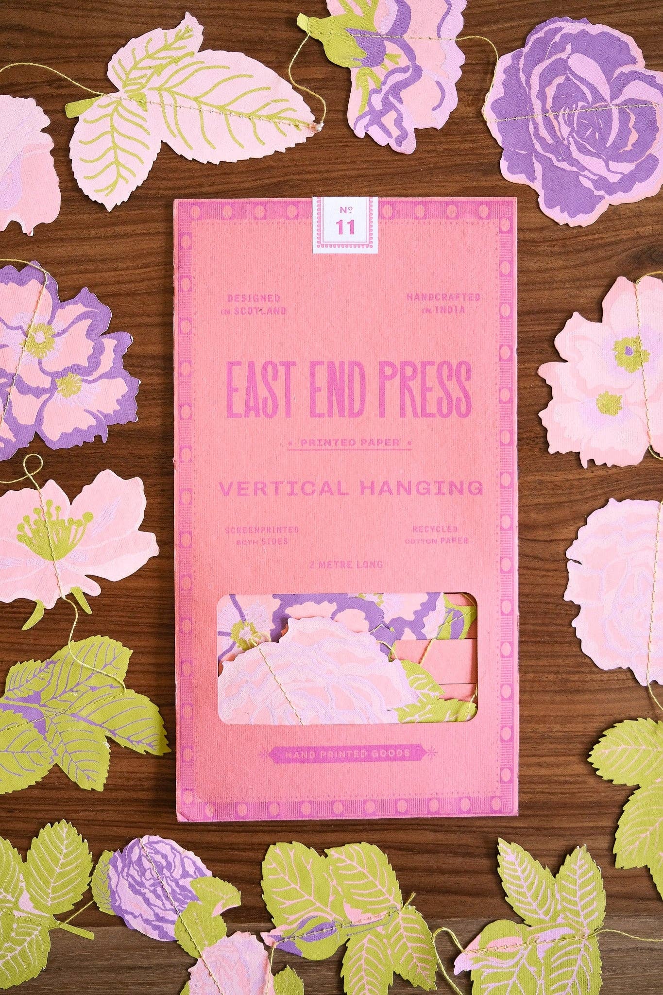 Pink packaging of East End Press on a wooden surface with floral decorations